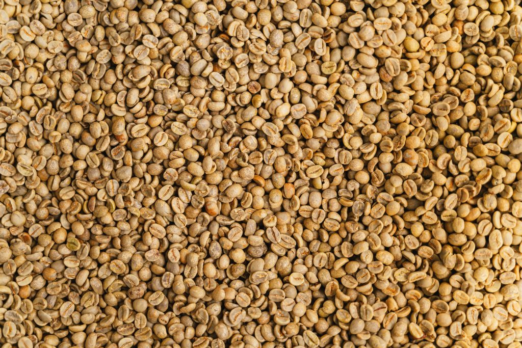 Close-up view of raw unroasted coffee beans showcasing a detailed texture ideal for backgrounds.